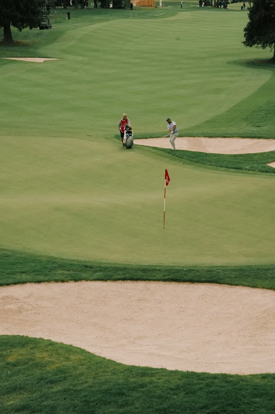 Golfers on a green beside a sand bunker
