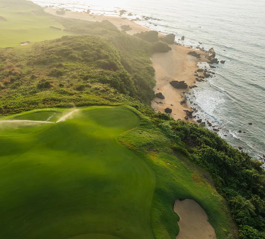 Aerial view of a cliff-top golf green above a rocky beach on Bali's west coast