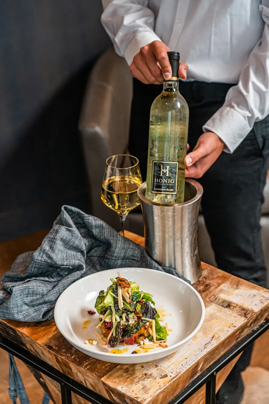 Waiter uncorking white wine beside a plated dish