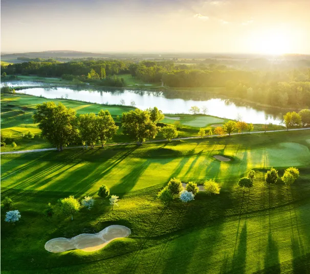 Aerial view of fairways, bunkers and a lake at sunset