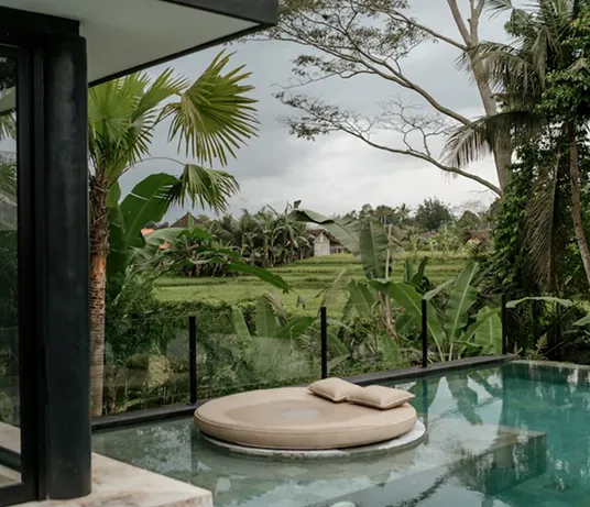 Private plunge pool with a round daybed overlooking rice fields